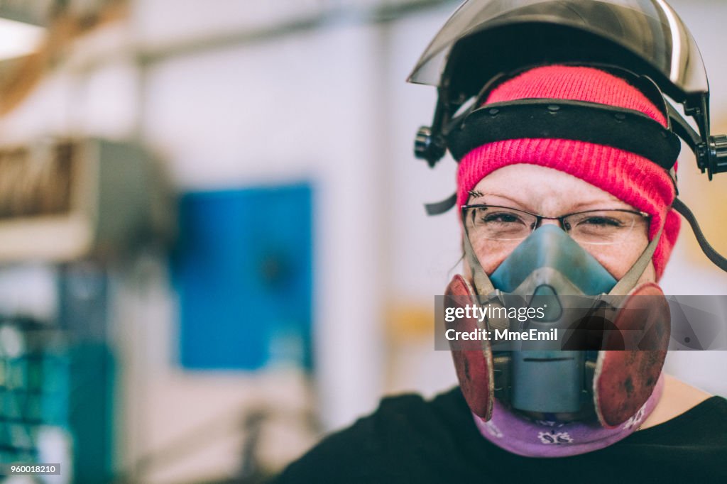Female worker wearing a mask and helmet. Smiling at camera