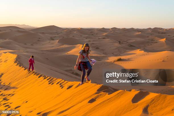 girls walking on sand dunes in sahara desert, merzouga, morocco - erg chebbi desert stock pictures, royalty-free photos & images
