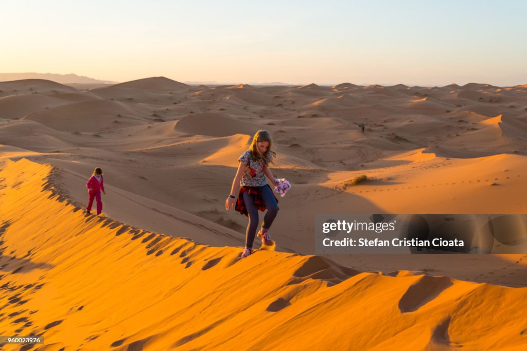 Girls walking on sand dunes in Sahara desert, Merzouga, Morocco