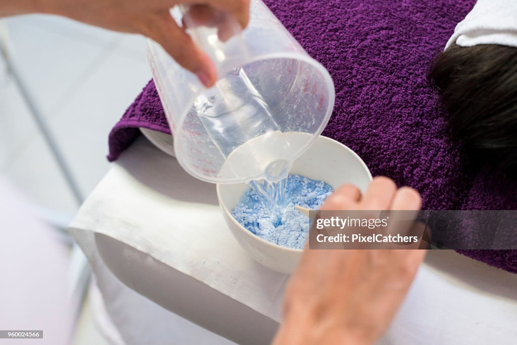 Beauty therapist preparing mask for a facial