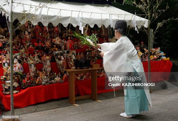Shinto priest offers a prayer for old dolls displayed on an altar during a 'doll funeral' at Sakaki Shrine in Tokyo on May 19, 2018. - Doll maker...