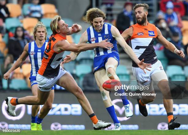 Ben Brown of the Kangaroos kicks whilst being tackled by Lachlan Keeffe of the Giants during the round nine AFL match between the North Melbourne...