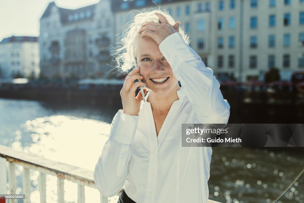 Happy businesswoman standing in front of a river.