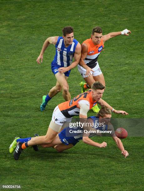 Jed Anderson of the Kangaroos handballs whilst being tackled by Aidan Corr of the Giants during the round nine AFL match between the North Melbourne...