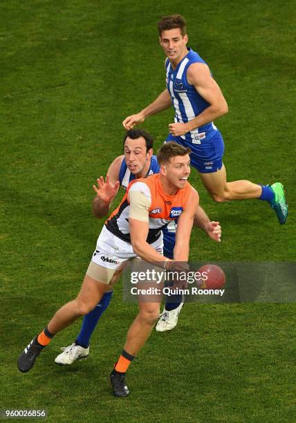 Aidan Corr of the Giants handballs whilst being tackled by Todd Goldstein of the Kangaroos during the round nine AFL match between the North...