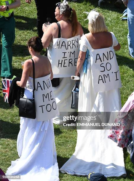 Well-wishers wear mock wedding dresses with banners reading "Harry, I'm Here", and "And So I Am I.." as they gather on the Long Walk leading to...