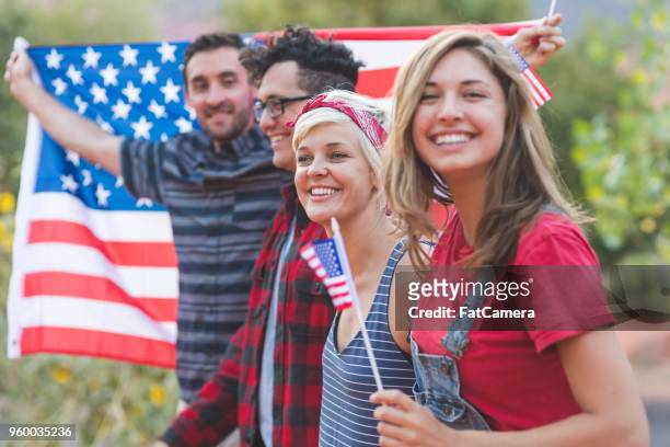 group of millennial friends hold a large american flag - america parade imagens e fotografias de stock