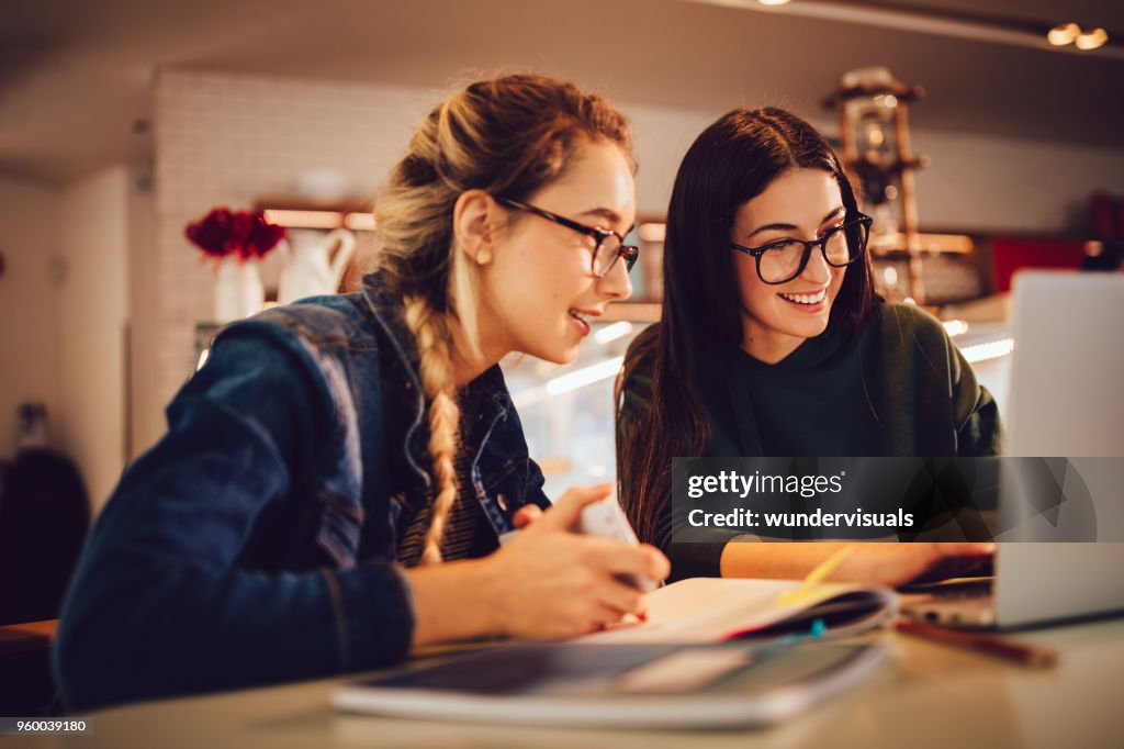 Vrouwelijke universitaire studenten met laptop samen studeren bij koffie shop