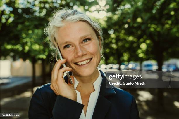 smiling businesswoman phoning in a park. - guido mieth - fotografias e filmes do acervo