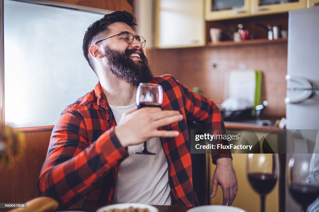 Vrolijke bebaarde man in geruite hemd drinken van wijn