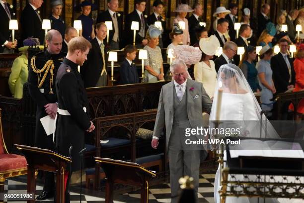 Prince Harry looks at his bride, Meghan Markle, as she arrives accompanied by Prince Charles, Prince of Wales during their wedding in St George's...