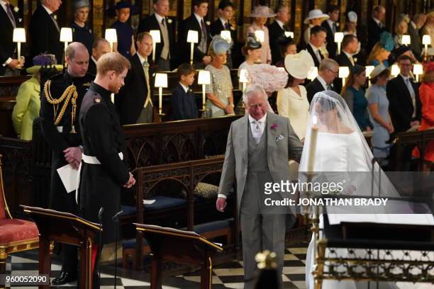 Britain's Prince Harry, Duke of Sussex , looks at his bride, Meghan Markle, as she arrives accompanied by the Britain's Prince Charles, Prince of...