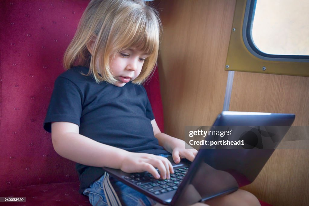 Little child using laptop on train