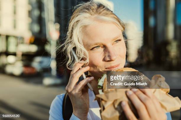 smiling businesswoman having breakfast while phoning. - guido mieth - fotografias e filmes do acervo