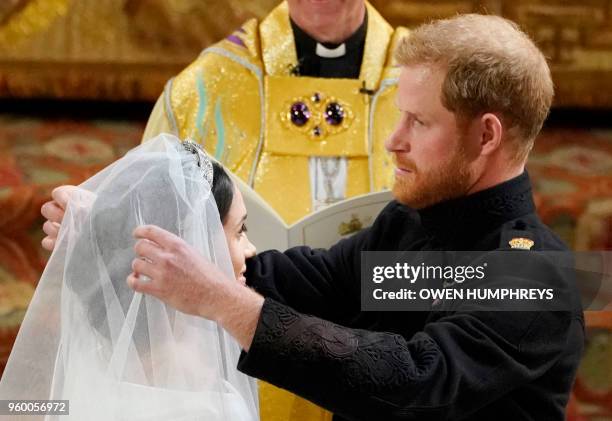 Britain's Prince Harry, Duke of Sussex removes the veil of US actress Meghan Markle as they stand at the altar together before Archbishop of...