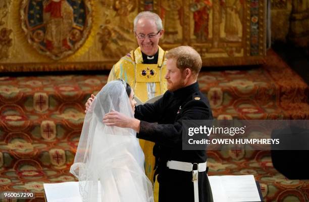 Britain's Prince Harry, Duke of Sussex removes the veil of US actress Meghan Markle as they stand at the altar together before Archbishop of...