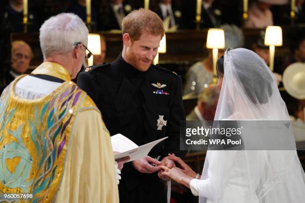 Prince Harry places the wedding ring on the finger of Meghan Markle during their wedding service, conducted by the Archbishop of Canterbury Justin...