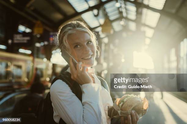 smiling businesswoman eating a bagel. - railroad station stock pictures, royalty-free photos & images