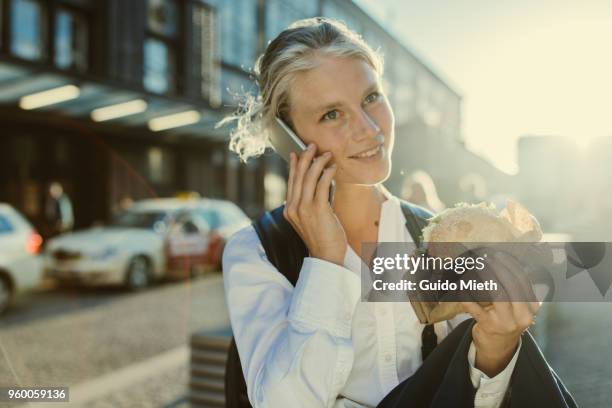 Smiling businesswoman eating a bagel.