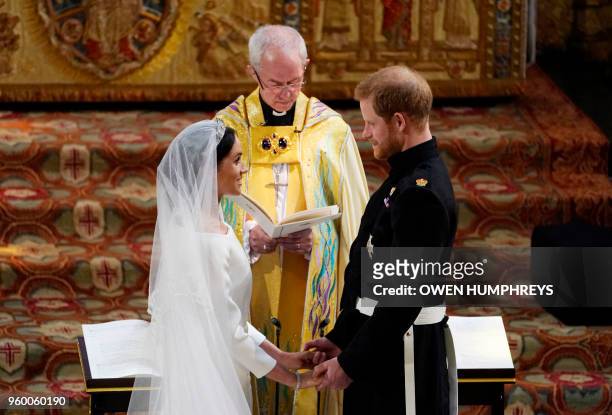 Britain's Prince Harry, Duke of Sussex and US actress Meghan Markle stand facing each other hand-in-hand before Archbishop of Canterbury Justin Welby...