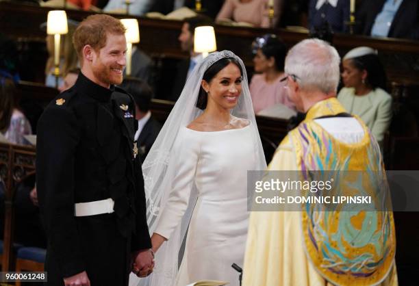 Britain's Prince Harry, Duke of Sussex and US fiancee of Britain's Prince Harry Meghan Markle stand together hand in hand at the High Altar during...