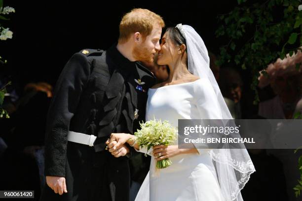 Britain's Prince Harry, Duke of Sussex kisses his wife Meghan, Duchess of Sussex as they leave from the West Door of St George's Chapel, Windsor...