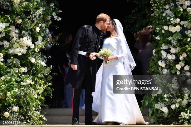 Britain's Prince Harry, Duke of Sussex kisses his wife Meghan, Duchess of Sussex as they leave from the West Door of St George's Chapel, Windsor...