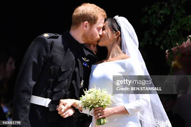 Britain's Prince Harry, Duke of Sussex kisses his wife Meghan, Duchess of Sussex as they leave from the West Door of St George's Chapel, Windsor...