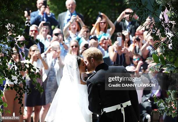 Britain's Prince Harry, Duke of Sussex kisses his wife Meghan, Duchess of Sussex as they leave from the West Door of St George's Chapel, Windsor...