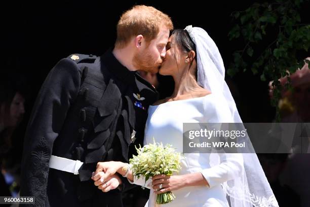 Britain's Prince Harry, Duke of Sussex kisses his wife Meghan, Duchess of Sussex as they leave from the West Door of St George's Chapel, Windsor...