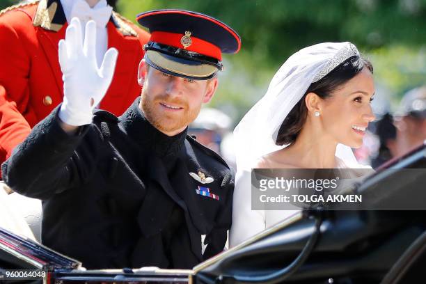 Britain's Prince Harry, Duke of Sussex and his wife Meghan, Duchess of Sussex wave from the Ascot Landau Carriage during their carriage procession on...