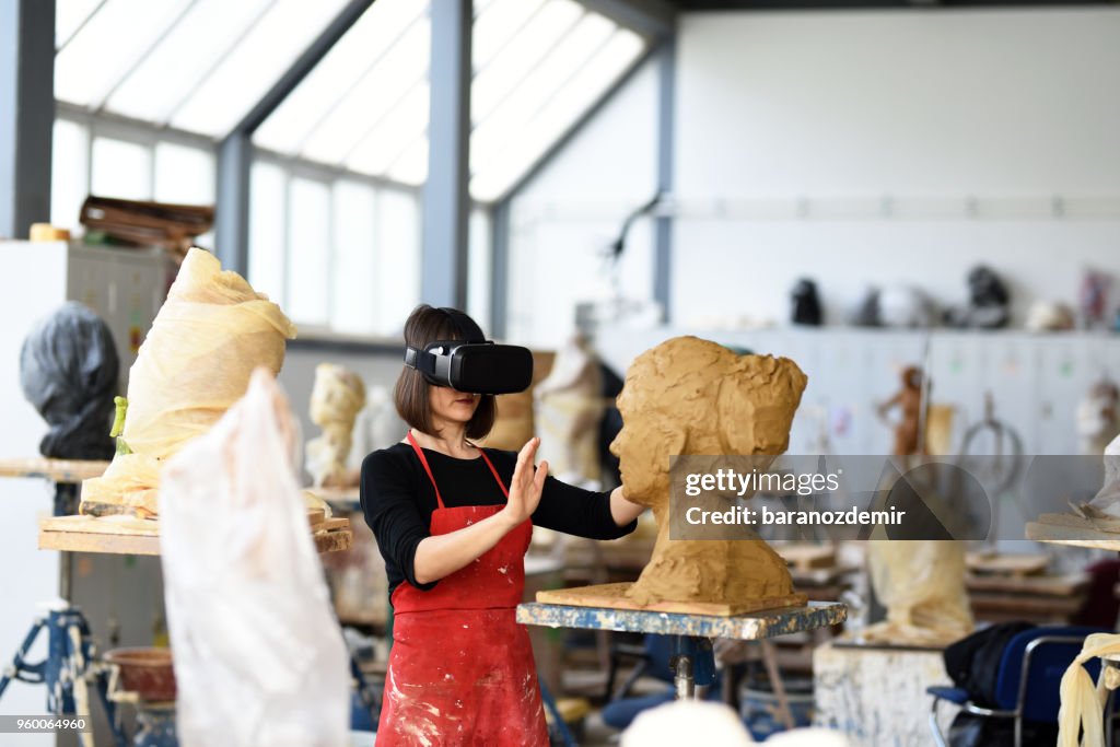 Young Female Sculptor is working with VR in her studio