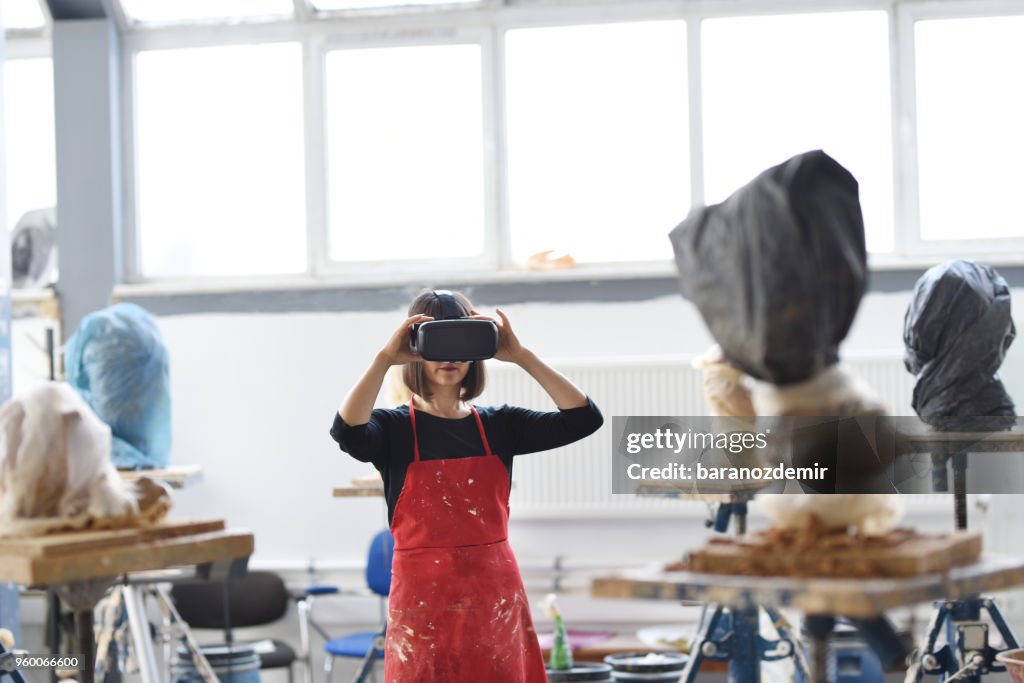 年輕的女雕塑家與 VR 在她的工作室