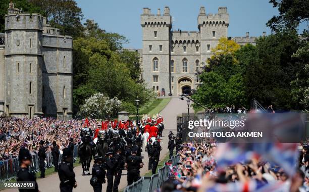 Britain's Prince Harry, Duke of Sussex and his wife Meghan, Duchess of Sussex wave from the Ascot Landau Carriage during their carriage procession on...