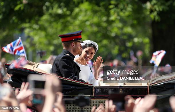 Britain's Prince Harry, Duke of Sussex and his wife Meghan, Duchess of Sussex wave from the Ascot Landau Carriage during their carriage procession on...