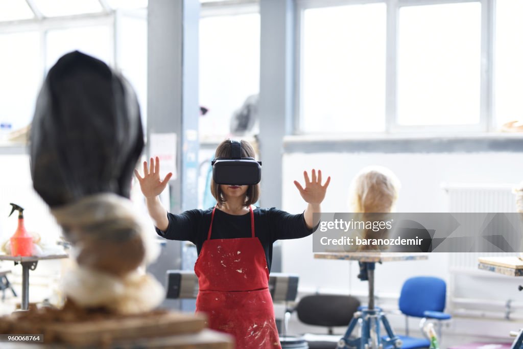Junge weibliche Bildhauer arbeitet mit VR im Atelier
