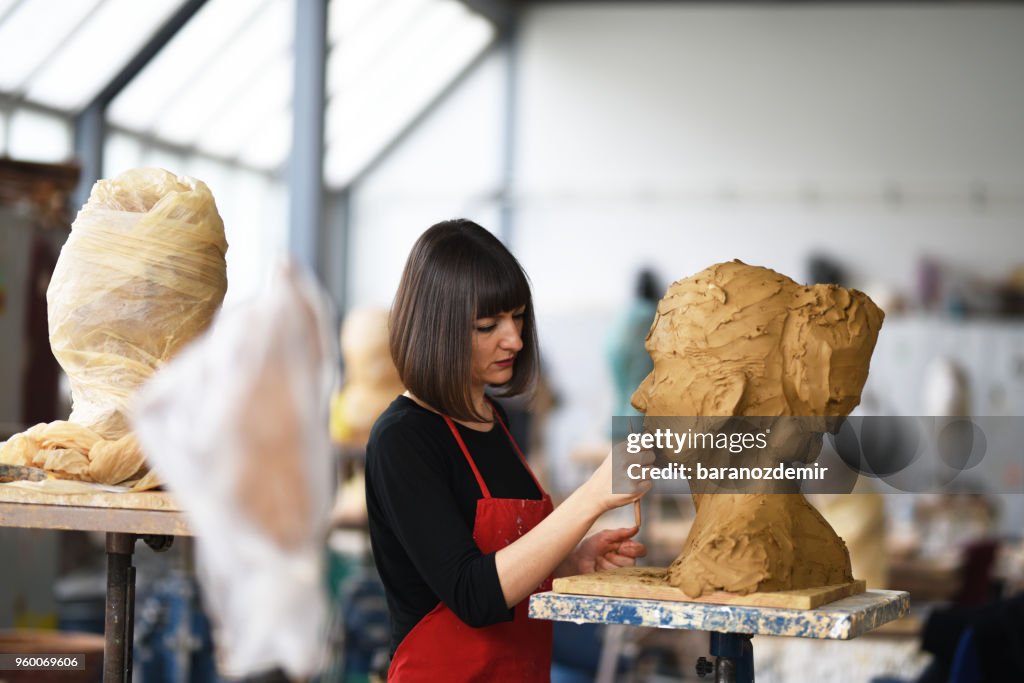 Young Female Sculptor is working in her studio
