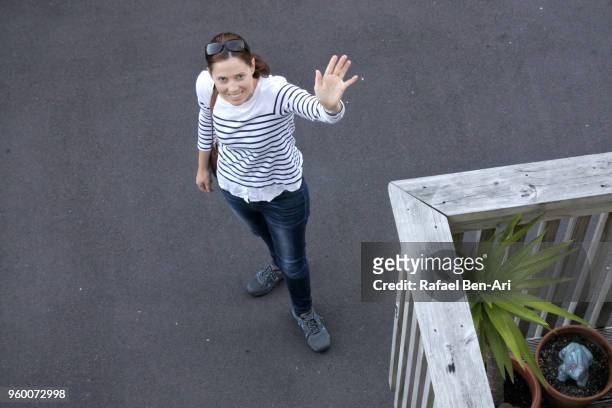 young adult woman waving goodbye before leaving home to work - rafael ben ari stock pictures, royalty-free photos & images