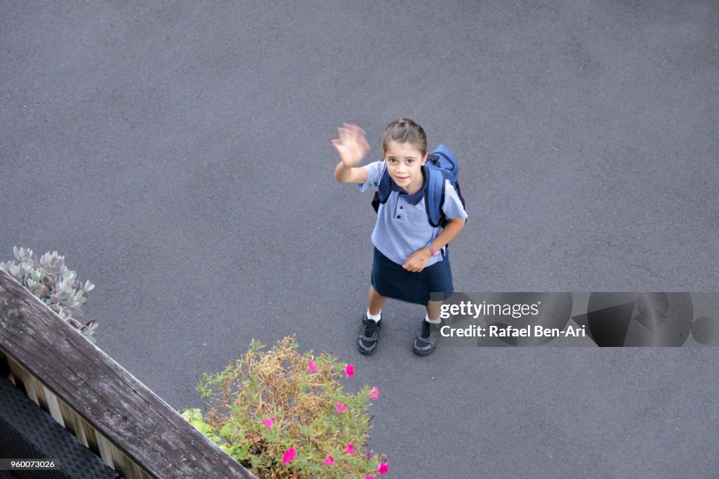 Young girl wave goodbye before going to school