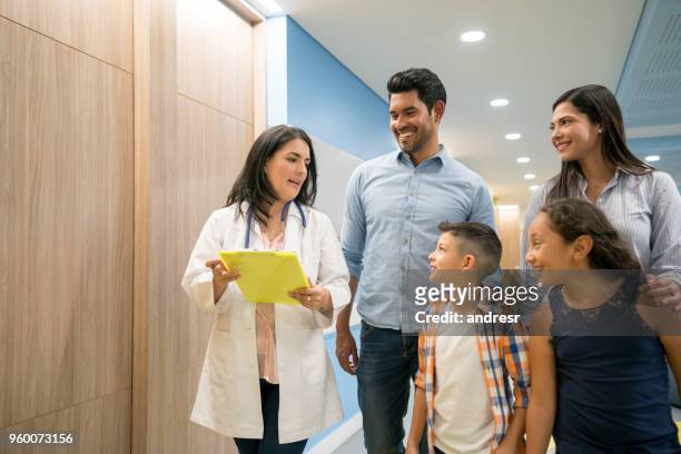 female doctor talking to patient while his family is listening and smiling - family with doctor stock pictures, royalty-free photos & images