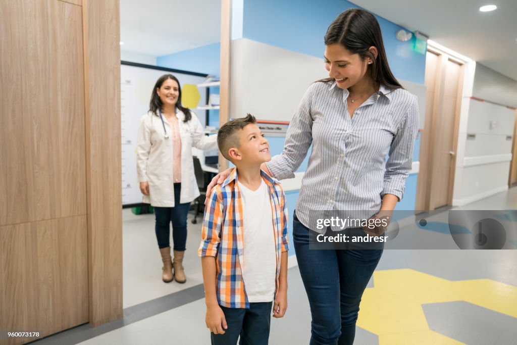 Amor madre e hijo andando de la oficina del doctor mientras ella los mira muy felices
