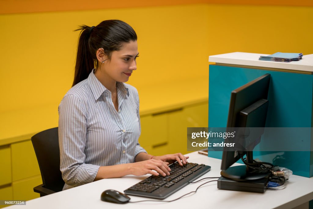 Assistente de latino-americanos a trabalhar na sua área de trabalho olhando muito concentrado e sorridente