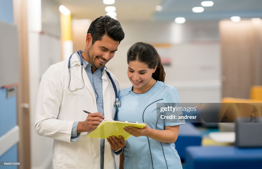 Young nurse looking at something the doctor is pointing on a clipboard both looking very happy