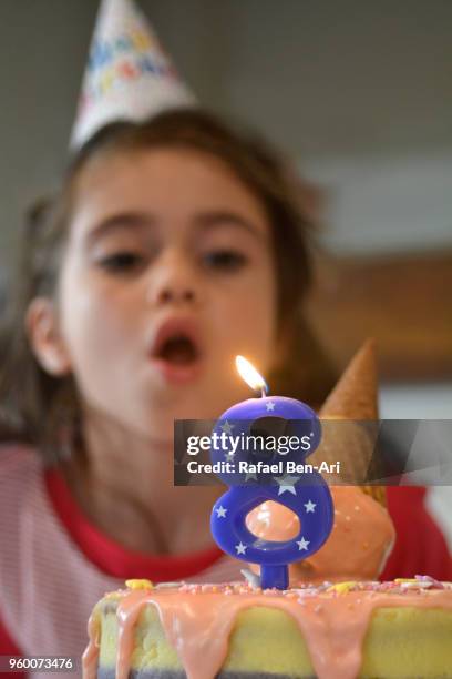 young girl blowing a candle on her 8th birthday - rafael ben ari fotografías e imágenes de stock