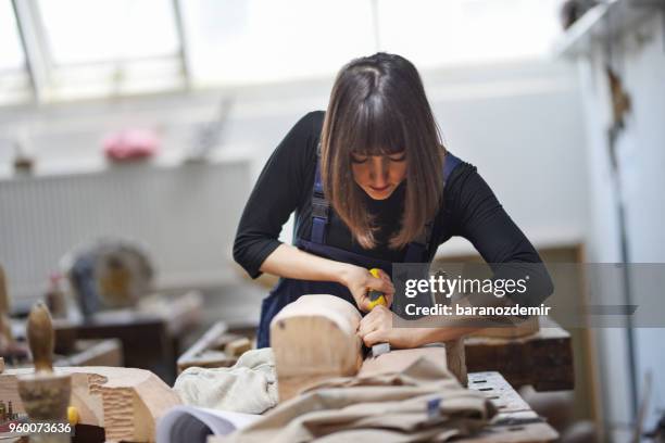 jeune femme sculpteur travaille dans son atelier - couteau à découper photos et images de collection