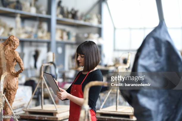 young female sculptor sta lavorando con il tablet digitale nel suo studio - baranozdemir foto e immagini stock
