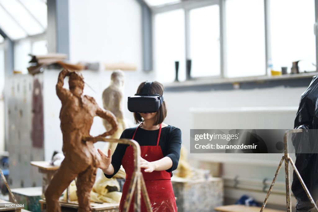 Young Female Sculptor is working with VR in her studio