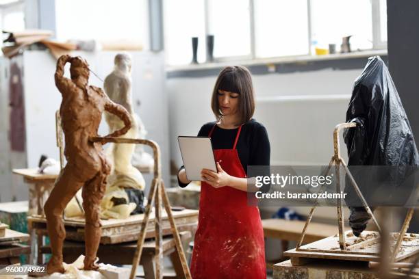 young female sculptor sta lavorando con il tablet digitale nel suo studio - baranozdemir foto e immagini stock