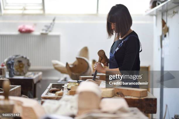 jeune femme sculpteur travaille dans son atelier - couteau à découper photos et images de collection