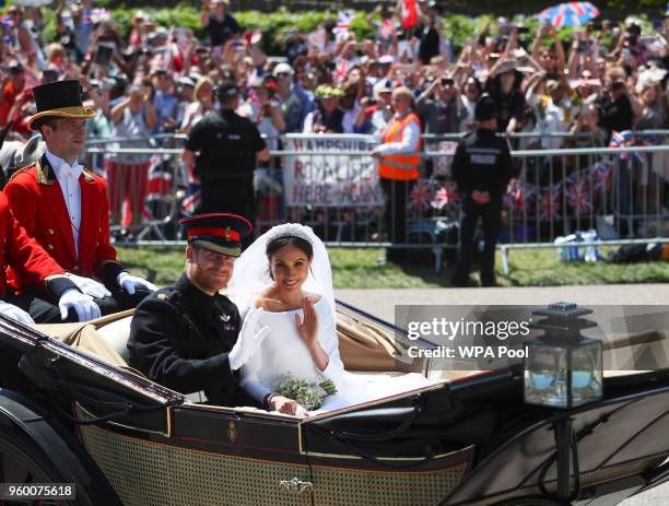 Prince Harry, Duke of Sussex and The Duchess of Sussex ride in the Ascot Landau carriage during a procession after getting married at St Georges...